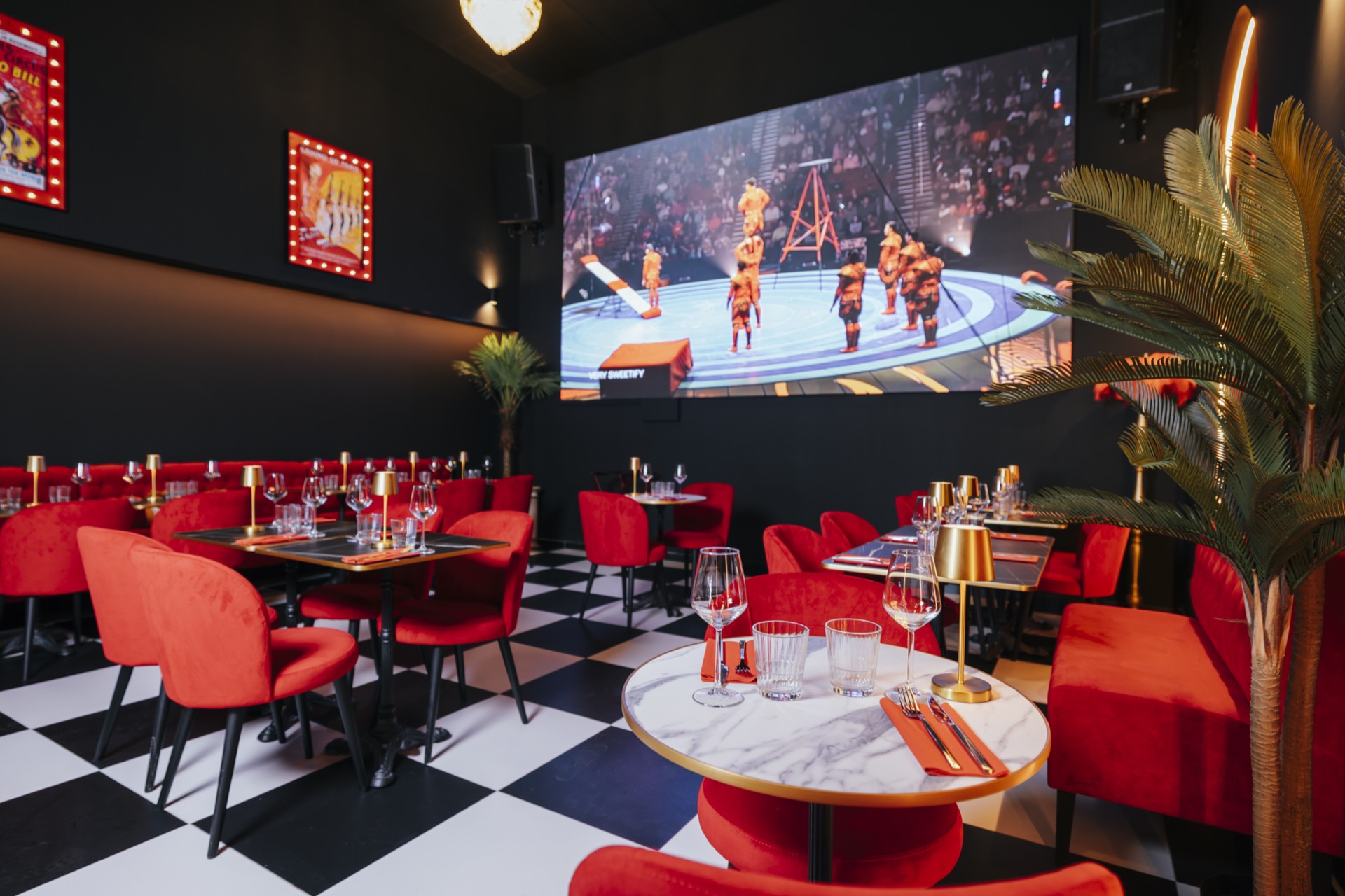 Salle restaurant CIRCUS avec écran géant, banquettes rouges et damier